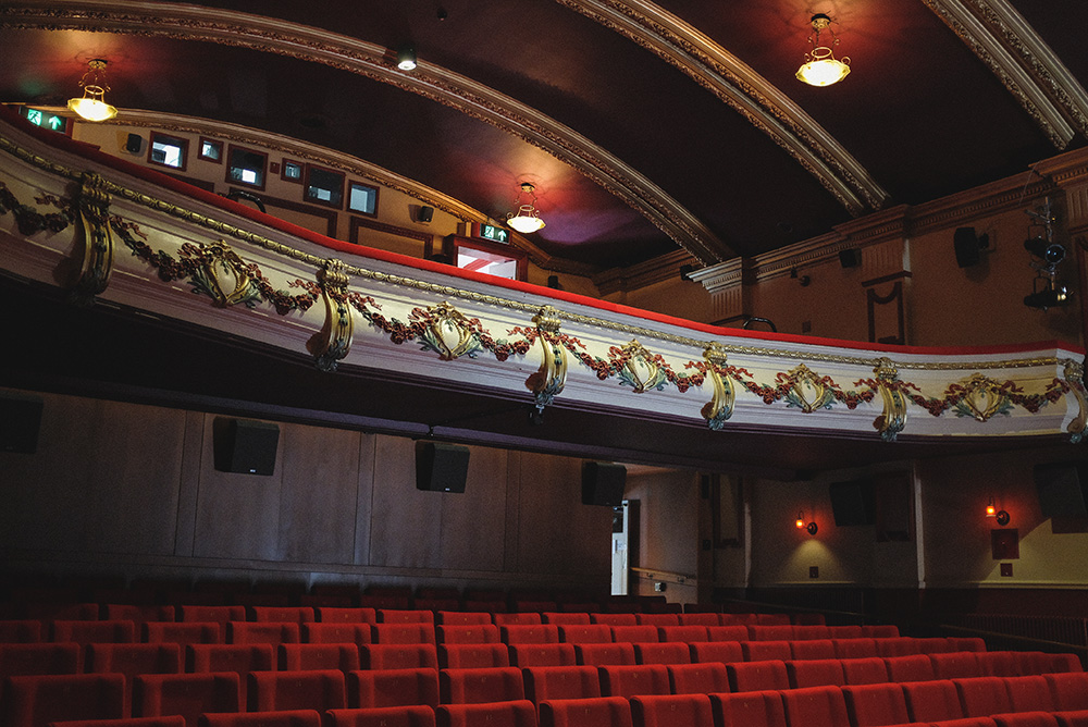 Taken from an extremely similar angle to the above image, it shows the cinema seats now in colour with high arch ceilings and plush red seats.