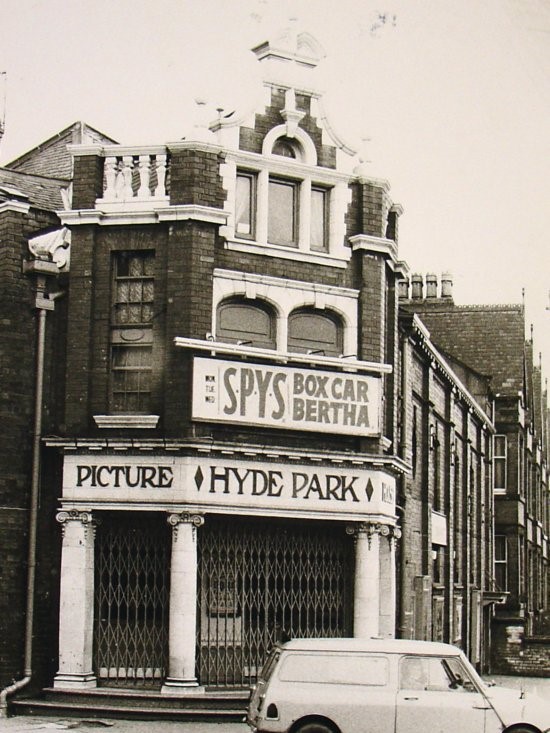 A black and white image of HPPH's exterior. The entrance is shut off by gates and a car is driving in front.