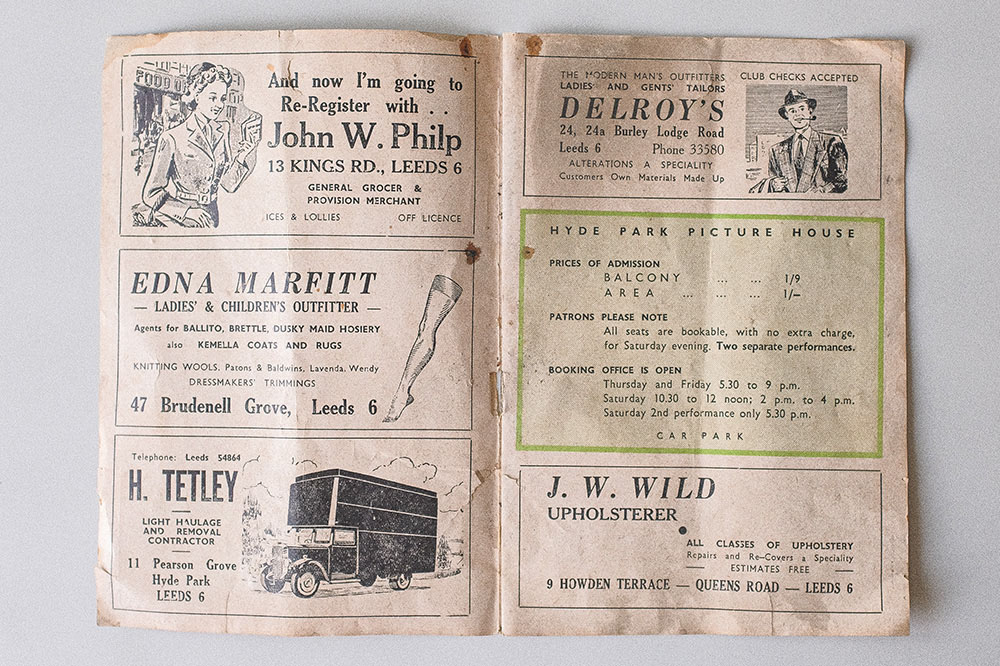 An open double page spread of an old programme. It contains 5 adverts advertising various goods and services such as alterations, upholstering, and movers.